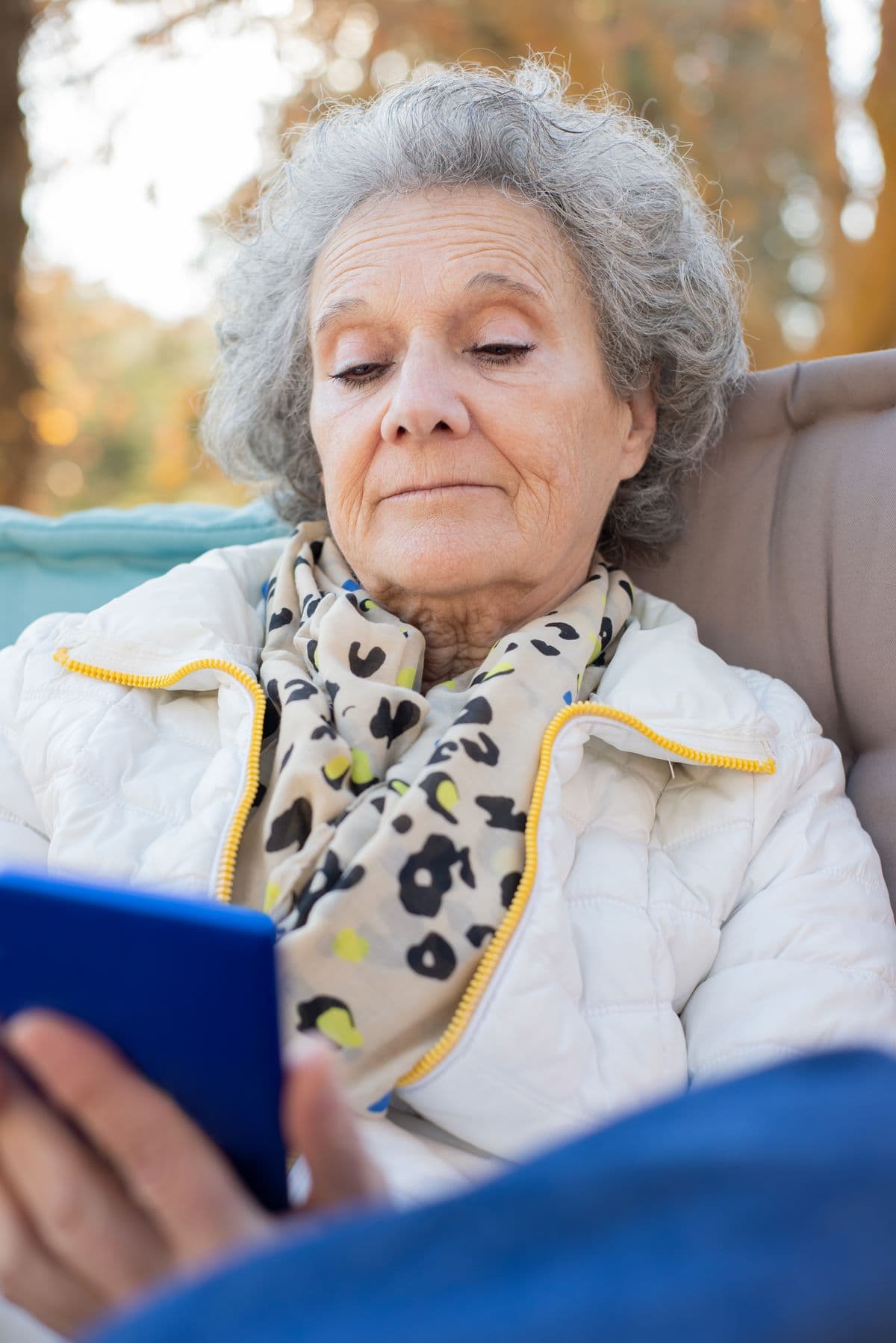 A senior woman outdoors, confidently using her smartphone on her own